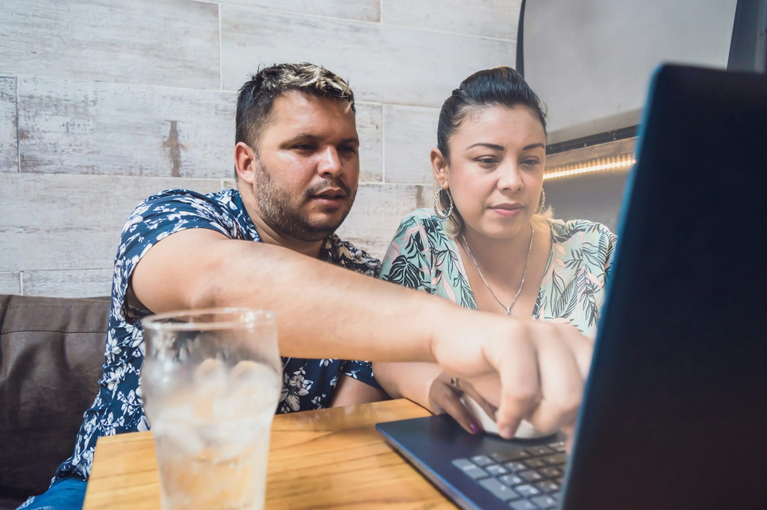 young couple of a boy and a woman using a computer in a coffee shop