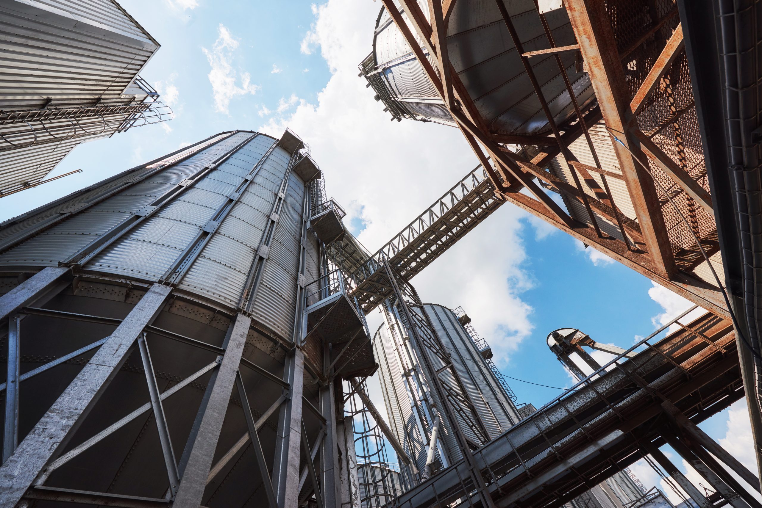 Agricultural Silos. Building Exterior. Storage and drying of grains, wheat, corn, soy, sunflower against the blue sky with white clouds