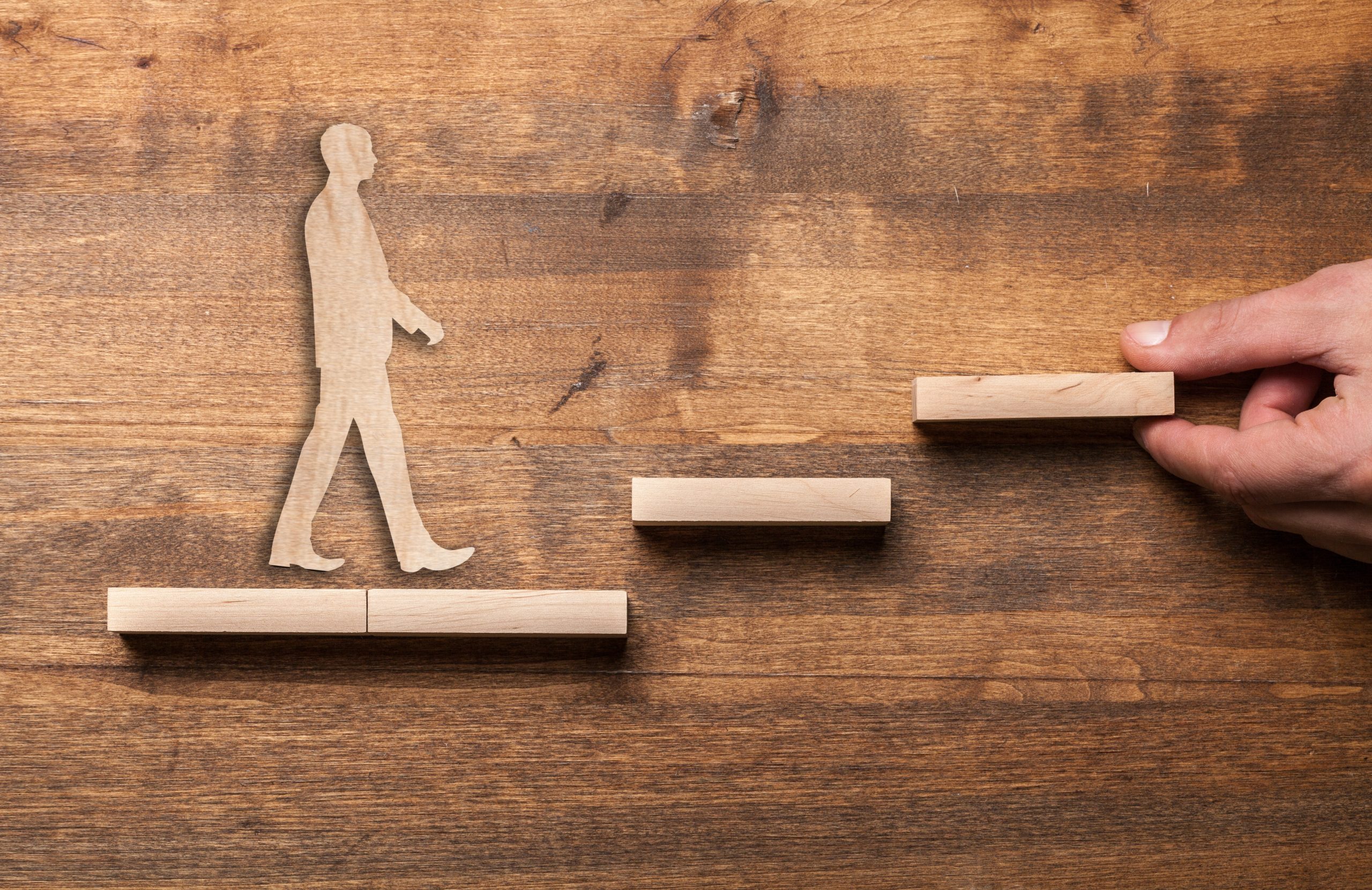 Success concept with wooden businessman climbing wooden block stairs